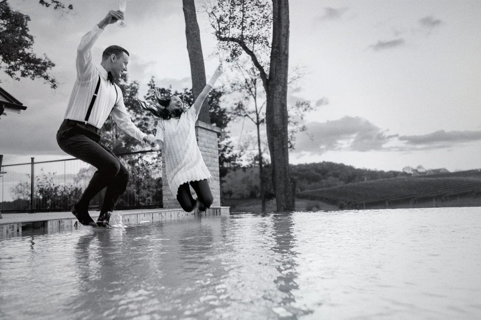 couple jumping into pool with clothes